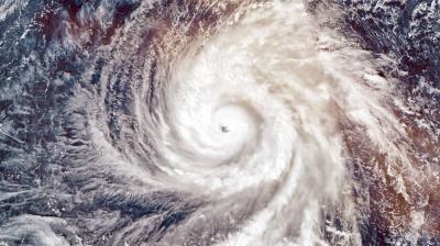 Satellite view of a swirling hurricane over the ocean, showing a distinct eye at the center surrounded by clouds.