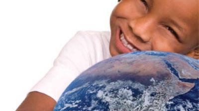 A smiling child in a white shirt hugs a globe, with the child's face and upper body partially visible against a white background.