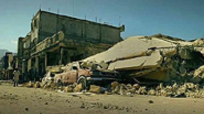 A collapsed building with debris covering a car on a street, suggesting recent earthquake damage and destruction.