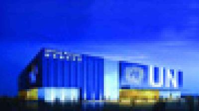 A modern building with a blue exterior and large white "UNI" letters on the facade, shown under a deep blue sky.