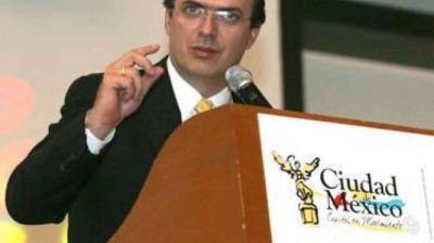 A man in a suit speaks at a podium labeled "Ciudad de México" with a microphone, making a gesture with his hand.