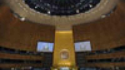 A large, round auditorium with wood-paneled walls, a central podium, and two projection screens, beneath a domed ceiling.