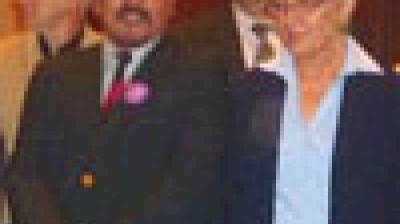 A group of people dressed in business attire stand close together, posing for a formal photograph indoors.