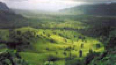 A blurry, pixelated image of a green valley surrounded by hills, with sunlight filtering through clouds above.