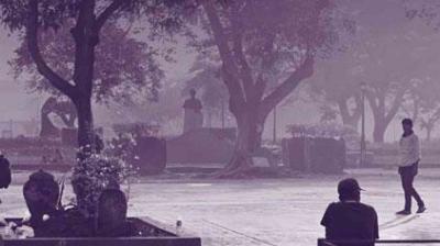 Several people are seen in a park with large trees and statues, while the air appears hazy or foggy.