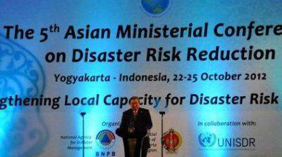A speaker stands on stage in front of a large banner for the 5th Asian Ministerial Conference on Disaster Risk Reduction held in Yogyakarta, Indonesia, October 22-25, 2012.