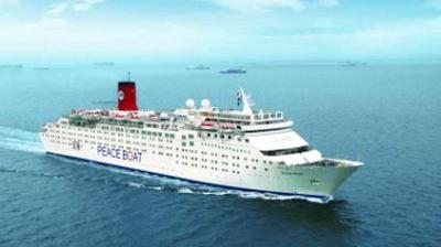 A white cruise ship labeled "Peace Boat" sails on calm blue ocean water under a clear sky, with other ships visible in the distant background.