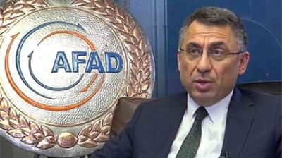 A man in a suit is seated next to an AFAD logo displayed on a large, round plaque.