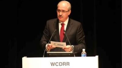 A man in a suit and tie speaks at a podium labeled "WCDRR.