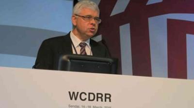 Man speaking at a podium during the WCDRR event.