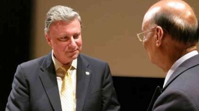 Two men in suits stand facing each other, engaged in conversation.