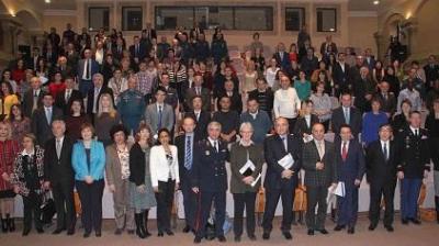 A large group of people, formally dressed, stand and sit in rows inside an auditorium, posing for a group photo.