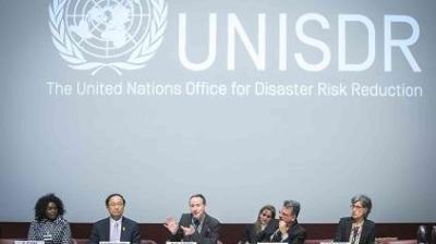 Panel discussion at a UNISDR event, with six people seated at a table in front of a large screen displaying the UNISDR logo and name.