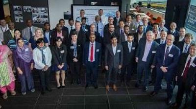 A diverse group of people in business attire posing for a group photo in a conference or meeting setting.