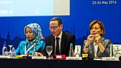 Three people sit at a conference table with microphones and nameplates in front of them, attending an event dated 23-24 May 2016.