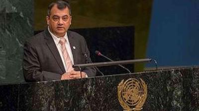 A man in a suit speaks at a podium with the United Nations emblem.