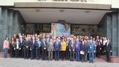 A large group of people in formal attire pose for a photo in front of a building entrance with a banner above the door.