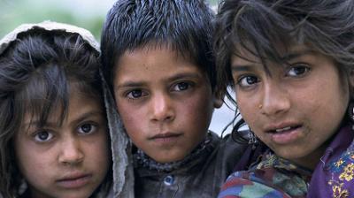 Three children with serious expressions stand close together, looking directly at the camera.