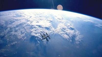 A large spacecraft orbits above Earth's surface, with clouds and blue atmosphere visible in the background.