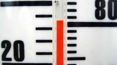 Close-up of a thermometer showing a temperature of approximately 70 degrees, with bold black markings on a white background and a red indicator.