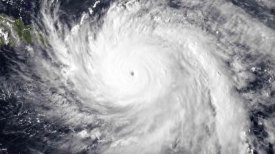 Satellite image of a large hurricane over the ocean, showing a distinct eye at the center surrounded by dense clouds.