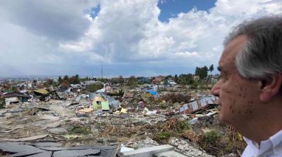 A person observes extensive destruction and debris in an urban area under a cloudy sky.