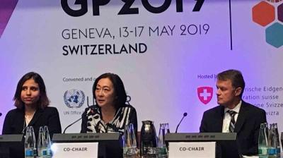 Three panelists seated at a table speak at the GP 2019 conference in Geneva, with microphones and nameplates.