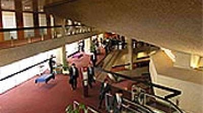 A view of a large indoor lobby with red carpet, people walking, multi-level walkways, and modern architecture.