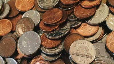 A pile of mixed coins, including Canadian pennies, nickels, and dimes, displaying various years and designs.