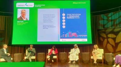Five panelists sit on a stage with a presentation screen displaying the "Global Methodology for Infrastructure Resilience Review" during the Innovate4Cities event.