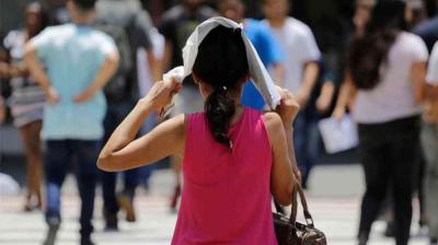 A woman covers her head with a cloth while walking outdoors among a crowd of people.