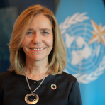 A woman smiling in front of a flag.